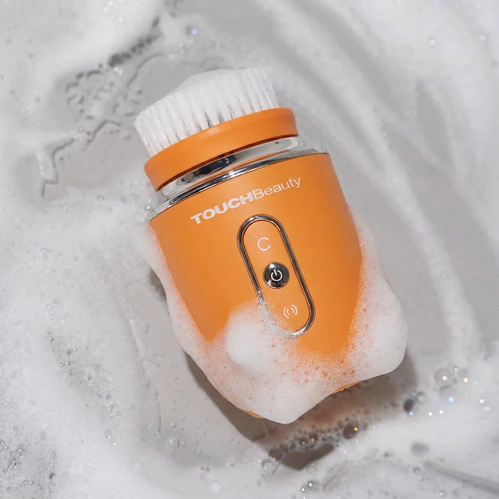 Cepillo facial AQUA naranja entre espuma de limpieza